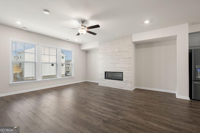 unfurnished living room featuring recessed lighting, a tiled fireplace, dark wood-type flooring, a ceiling fan, and baseboards