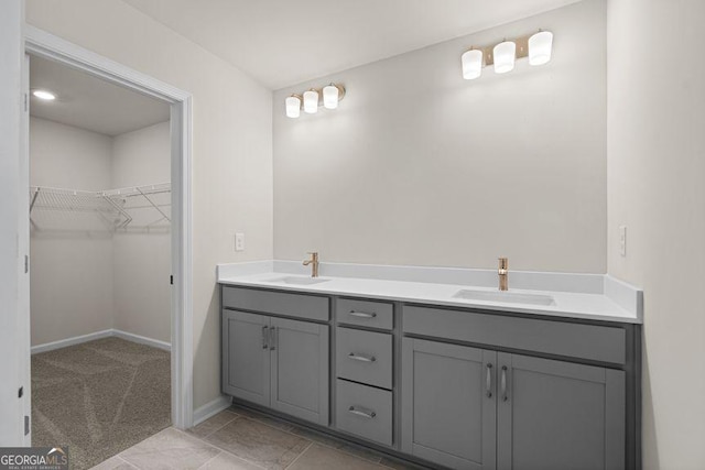 bathroom with double vanity, a spacious closet, a sink, and baseboards