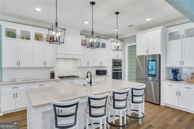 kitchen with stainless steel appliances, light countertops, and a kitchen island with sink