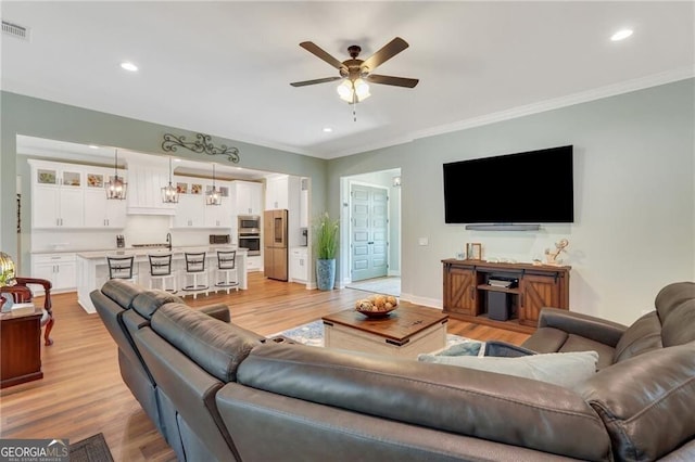 living area featuring ceiling fan, light wood-style flooring, recessed lighting, visible vents, and ornamental molding