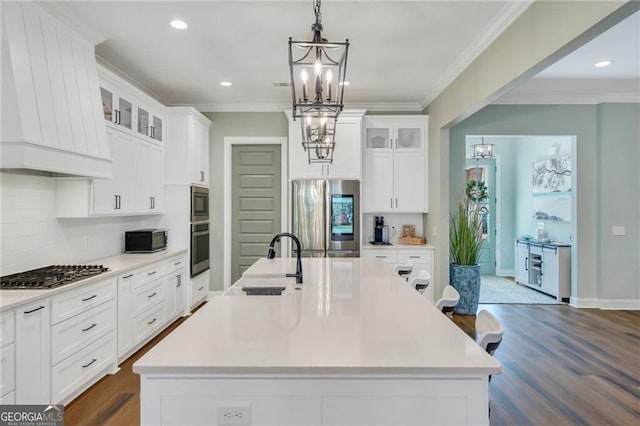 kitchen with stainless steel appliances, light countertops, and a kitchen island with sink