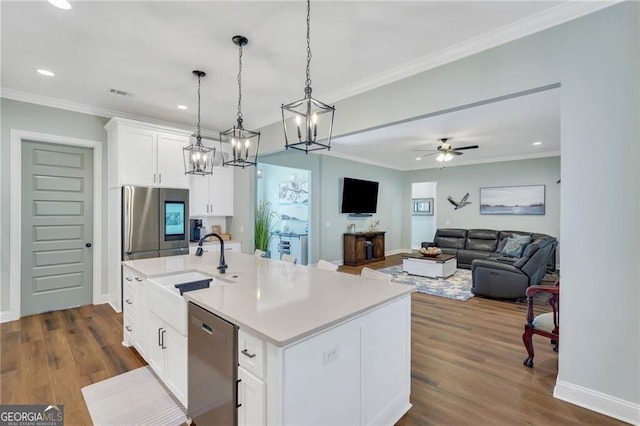 kitchen with white cabinetry, open floor plan, light countertops, appliances with stainless steel finishes, and a center island with sink