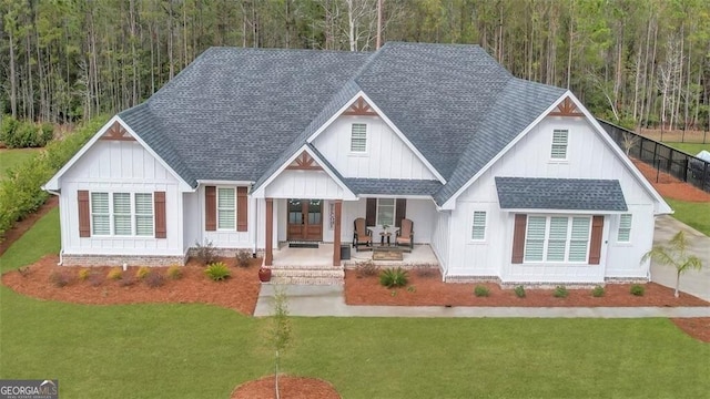 modern farmhouse style home with covered porch, roof with shingles, and a front yard