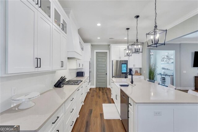 kitchen featuring light countertops, glass insert cabinets, a kitchen island with sink, and white cabinets