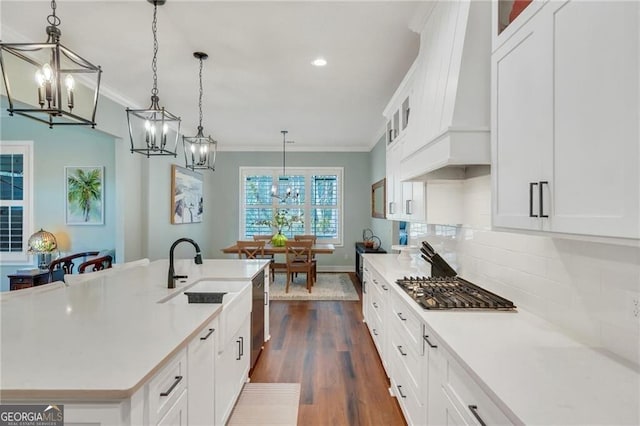 kitchen with hanging light fixtures, custom exhaust hood, a center island with sink, and white cabinets