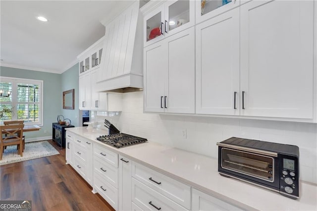 kitchen featuring crown molding, custom exhaust hood, light countertops, glass insert cabinets, and white cabinets