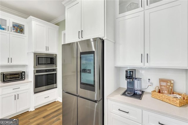 kitchen with tasteful backsplash, light countertops, appliances with stainless steel finishes, glass insert cabinets, and white cabinets