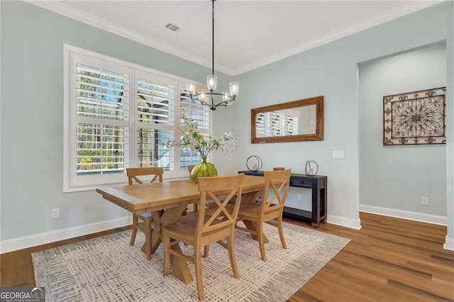 dining room with baseboards, wood finished floors, visible vents, and crown molding