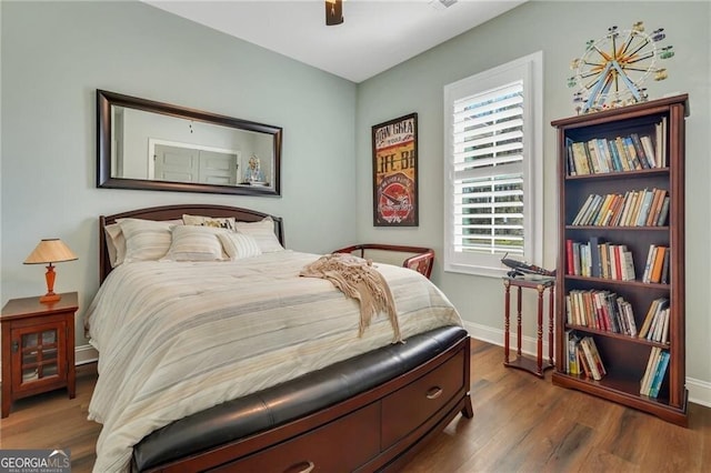 bedroom with dark wood-type flooring, ceiling fan, and baseboards