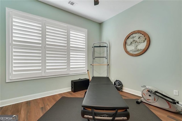 workout area featuring baseboards, visible vents, and wood finished floors