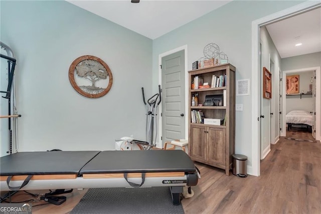 exercise room with light wood-style flooring and baseboards