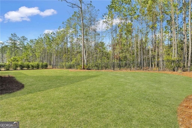 view of yard featuring a forest view and fence