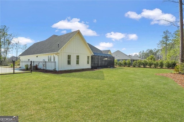 view of home's exterior with board and batten siding, glass enclosure, a lawn, and fence