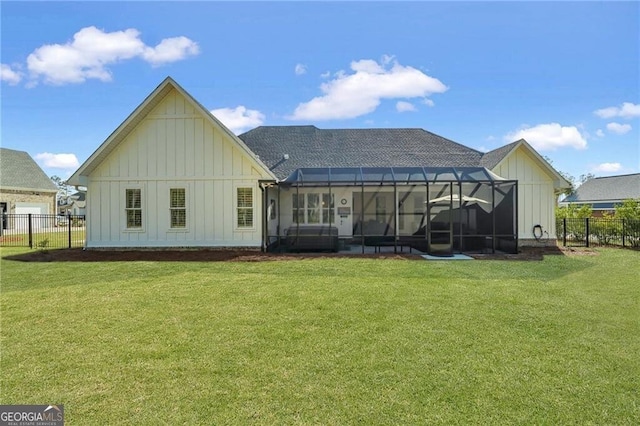 rear view of property featuring a lanai, fence, a lawn, roof with shingles, and board and batten siding