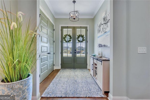 doorway featuring baseboards, wood finished floors, crown molding, french doors, and a chandelier