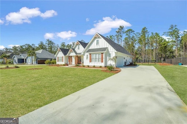 view of front of property featuring driveway, fence, board and batten siding, and a front yard