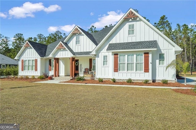 modern farmhouse style home with covered porch, roof with shingles, a front lawn, and board and batten siding