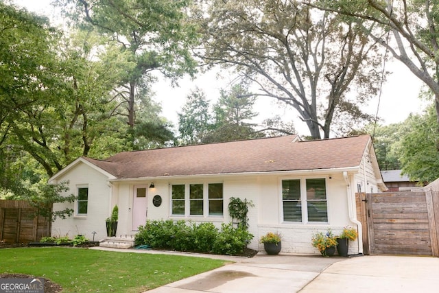 single story home with brick siding, a shingled roof, fence, and a front yard