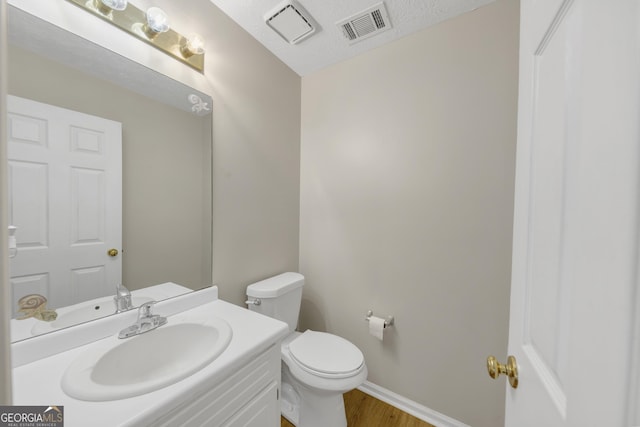 bathroom featuring toilet, vanity, visible vents, and baseboards