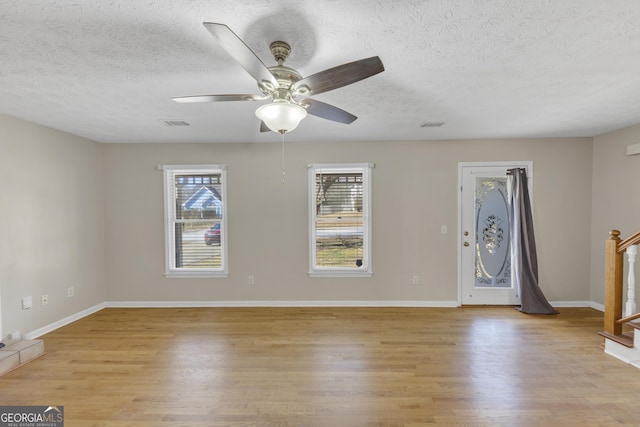 unfurnished living room featuring light wood finished floors, ceiling fan, baseboards, and a textured ceiling