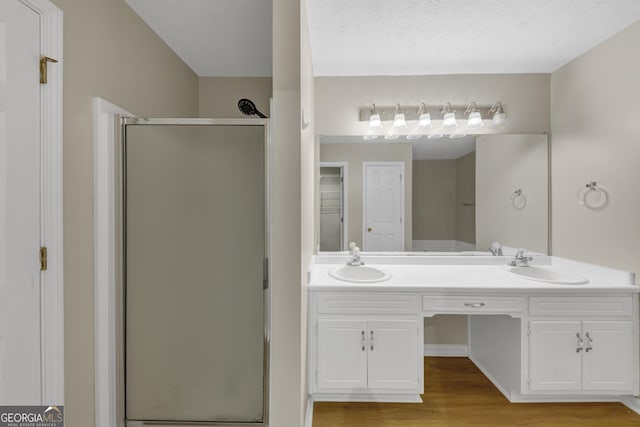 bathroom featuring a stall shower, a sink, and double vanity