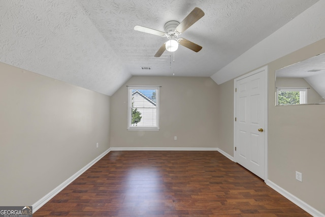 bonus room featuring plenty of natural light, vaulted ceiling, and dark wood finished floors