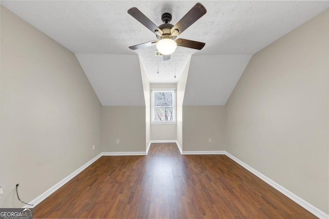 additional living space with lofted ceiling, baseboards, dark wood-type flooring, and a textured ceiling