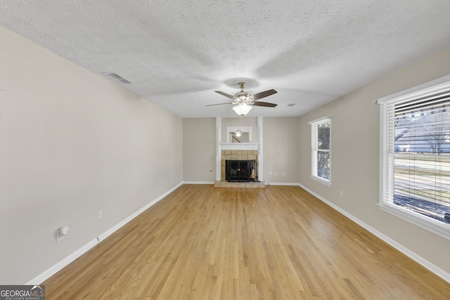 unfurnished living room featuring light wood-style flooring, a fireplace, baseboards, and a ceiling fan