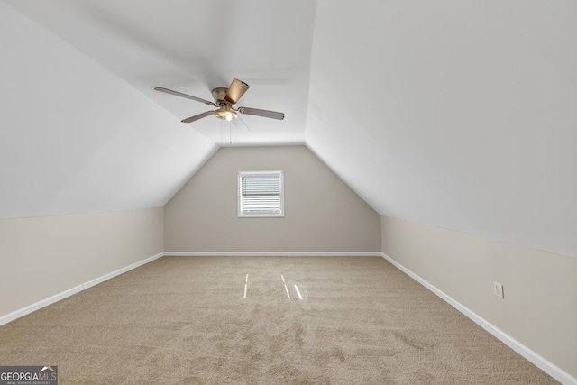 additional living space with a ceiling fan, light colored carpet, vaulted ceiling, and baseboards