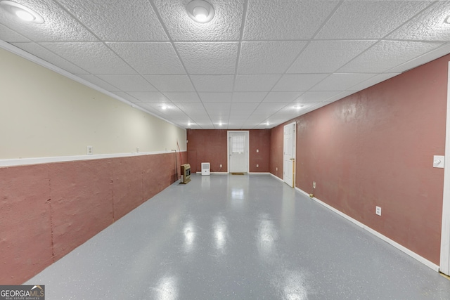 finished below grade area featuring a drop ceiling and baseboards