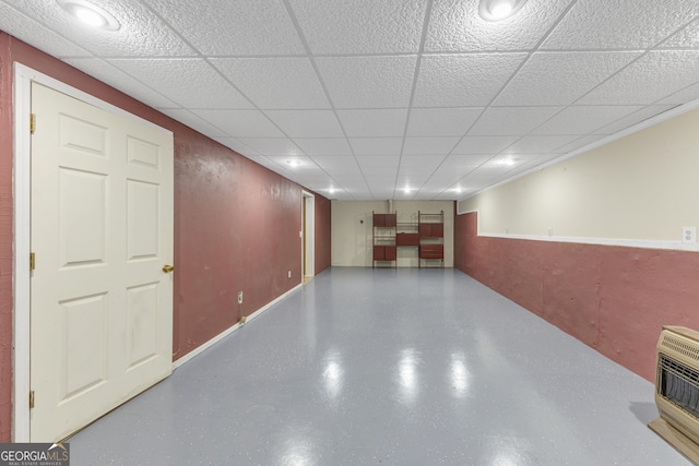 finished basement featuring a drop ceiling and heating unit