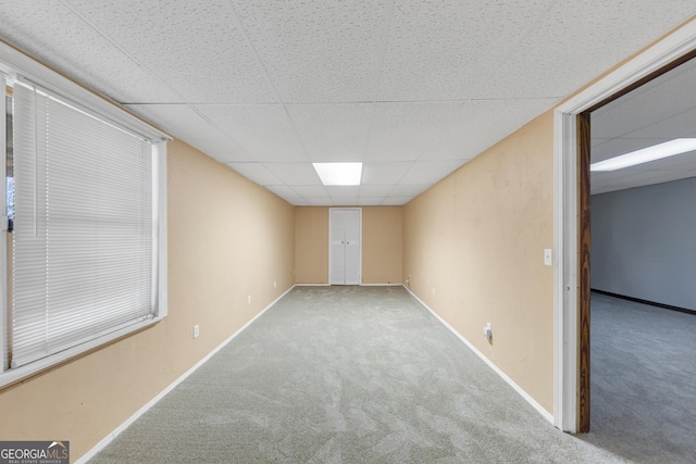 unfurnished room featuring baseboards, a paneled ceiling, and light colored carpet