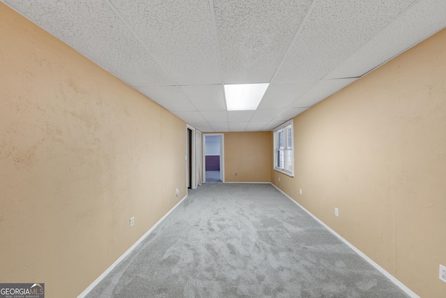 carpeted empty room with baseboards and a drop ceiling