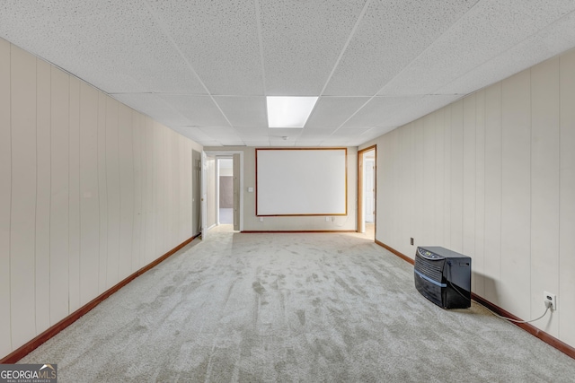 carpeted empty room with a drop ceiling and baseboards