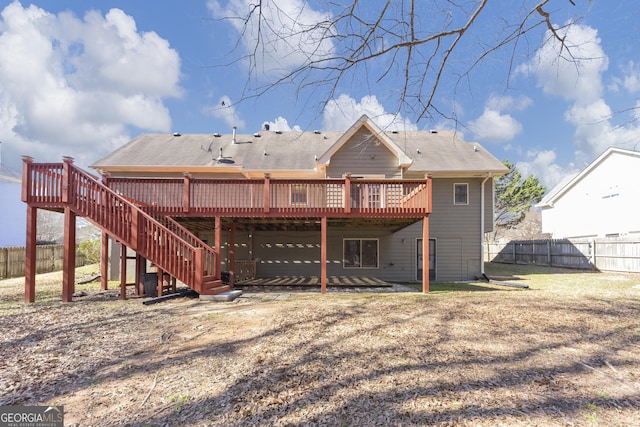 rear view of house with stairs, a yard, a wooden deck, and fence