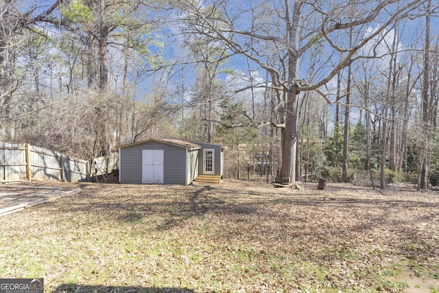 view of yard with entry steps, fence, an outdoor structure, and a shed