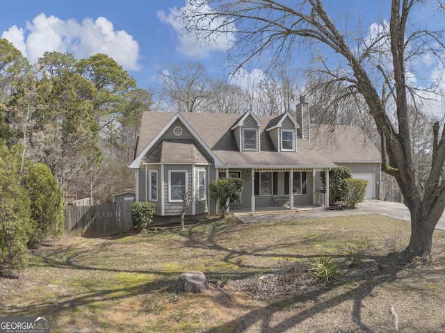 cape cod home featuring a porch, fence, concrete driveway, a front lawn, and a chimney