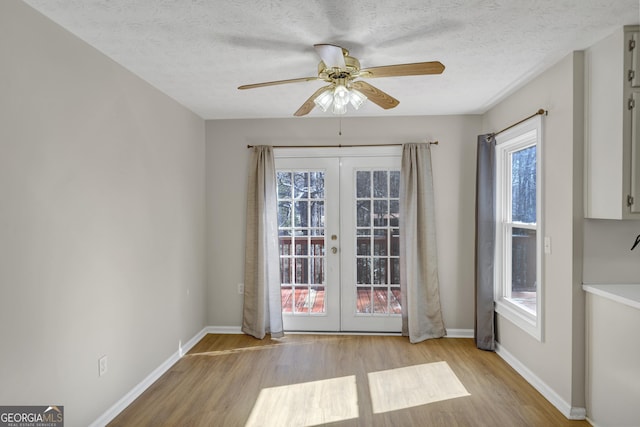 doorway featuring light wood-style floors, baseboards, a textured ceiling, and french doors