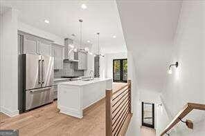 kitchen with light wood finished floors, light countertops, hanging light fixtures, a kitchen island, and high quality fridge