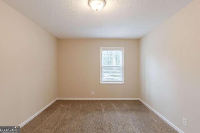 spare room featuring carpet, baseboards, and a textured ceiling