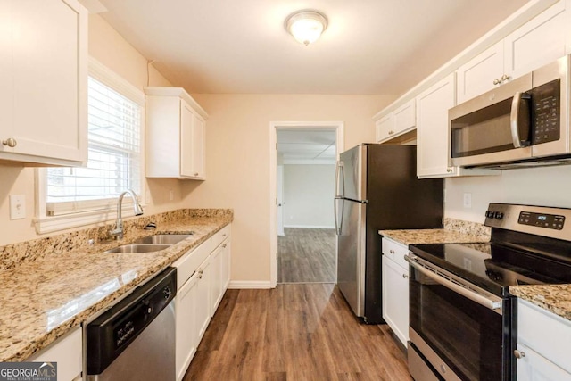 kitchen with white cabinets, light stone countertops, stainless steel appliances, and a sink