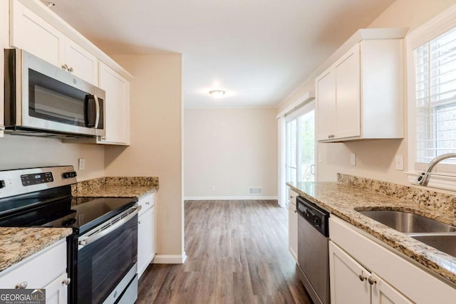 kitchen with a sink, white cabinetry, appliances with stainless steel finishes, and light stone counters