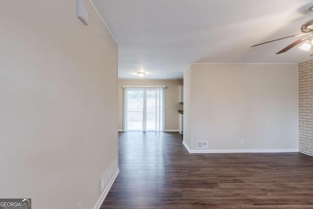 spare room featuring dark wood-type flooring, visible vents, ceiling fan, and baseboards