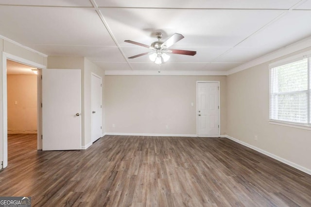 spare room featuring dark wood-style floors, a ceiling fan, and baseboards