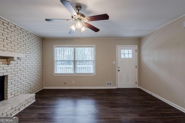 unfurnished living room featuring a brick fireplace, baseboards, dark wood-style floors, and visible vents