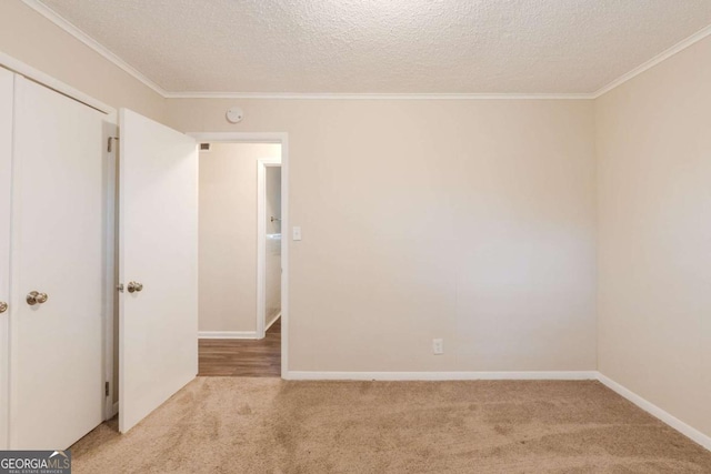 unfurnished room with baseboards, ornamental molding, a textured ceiling, and light colored carpet