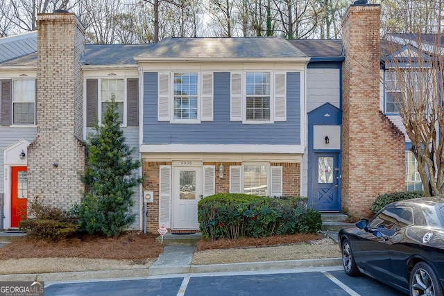 multi unit property with uncovered parking, brick siding, and a chimney