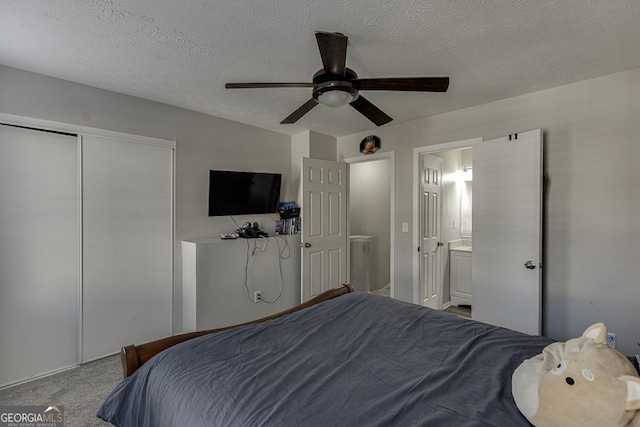 carpeted bedroom with connected bathroom, a closet, ceiling fan, and a textured ceiling