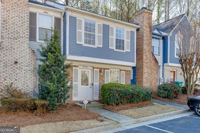 townhome / multi-family property featuring uncovered parking, brick siding, and a chimney