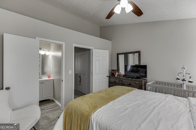 bedroom featuring a sink, vaulted ceiling, a textured ceiling, and ensuite bathroom